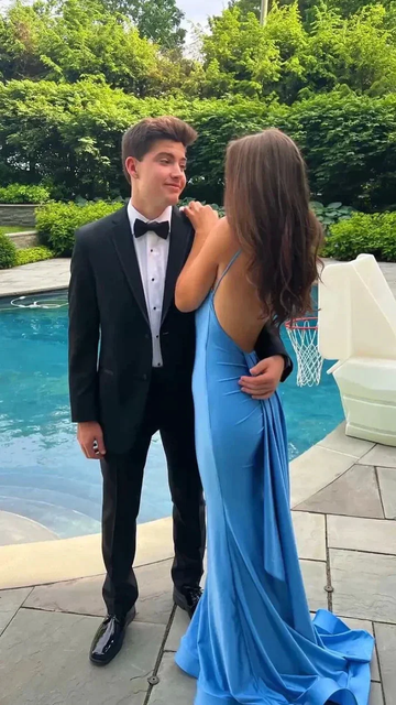 Young couple by pool, man in black tuxedo and woman in blue backless dress, prom style