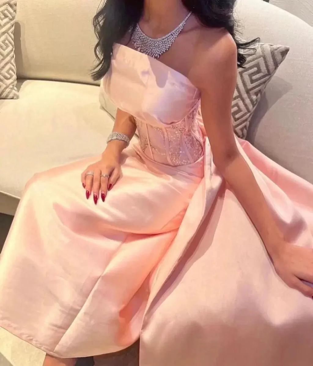 Woman in elegant blush pink strapless dress with jewelry, seated on sofa, ZAPDRESS fashion