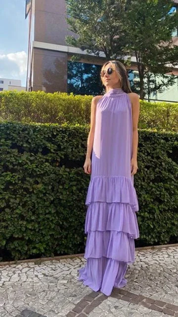 Woman in a sleeveless lilac tiered maxi dress from ZAPDRESS, outdoors with greenery