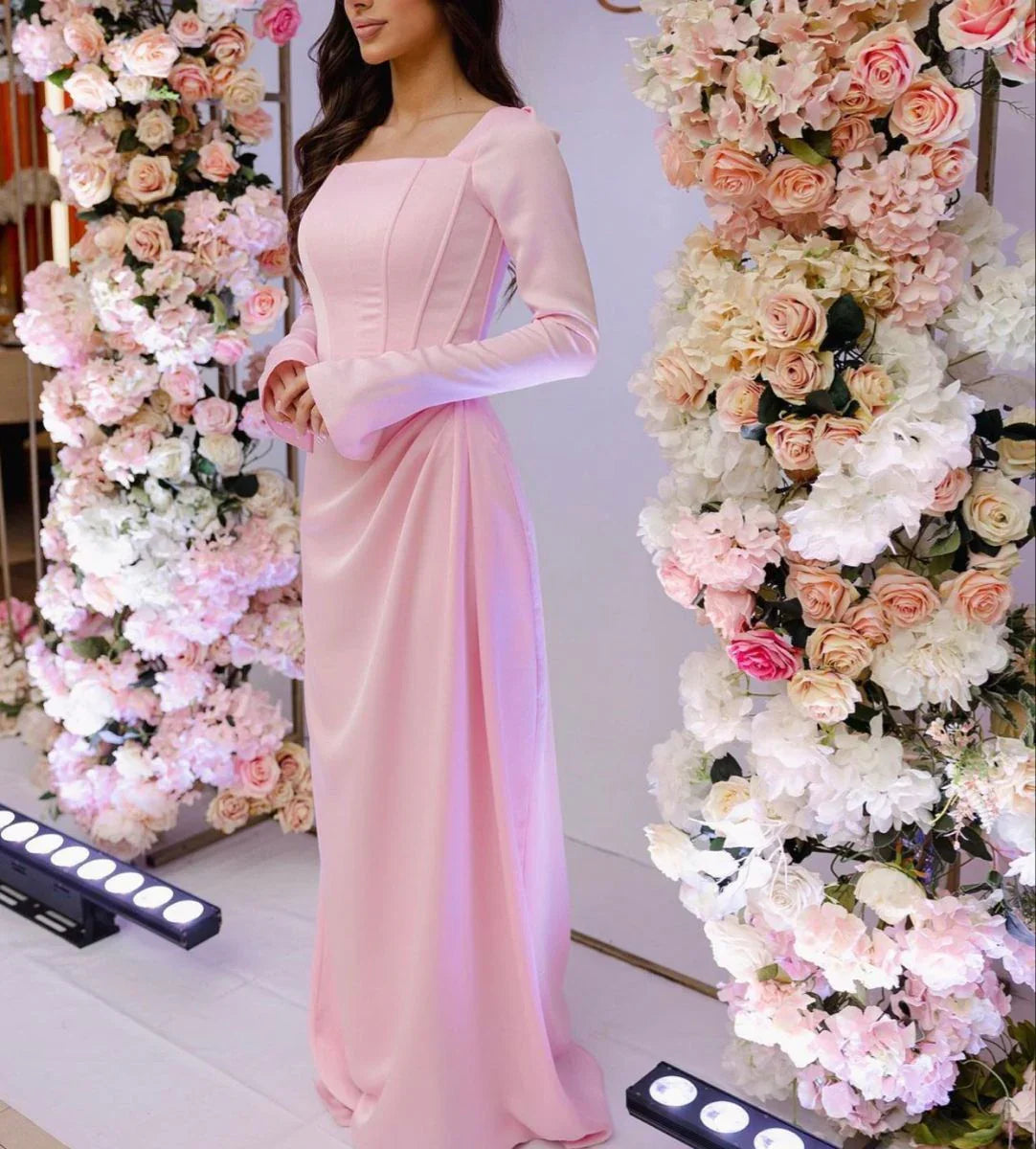 Woman in elegant pink long dress standing between floral arches, ZAPDRESS fashion