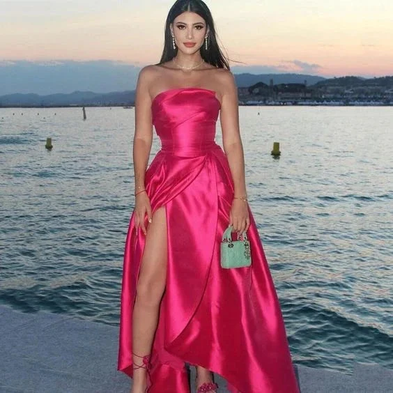 Woman in strapless hot pink satin evening dress with slit, holding mint handbag by waterfront, ZAPDRESS