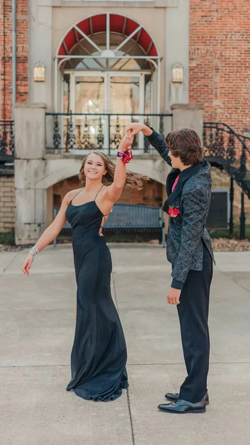 Prom couple dancing outdoors, woman in elegant black dress, matching corsages, ZAPDRESS style