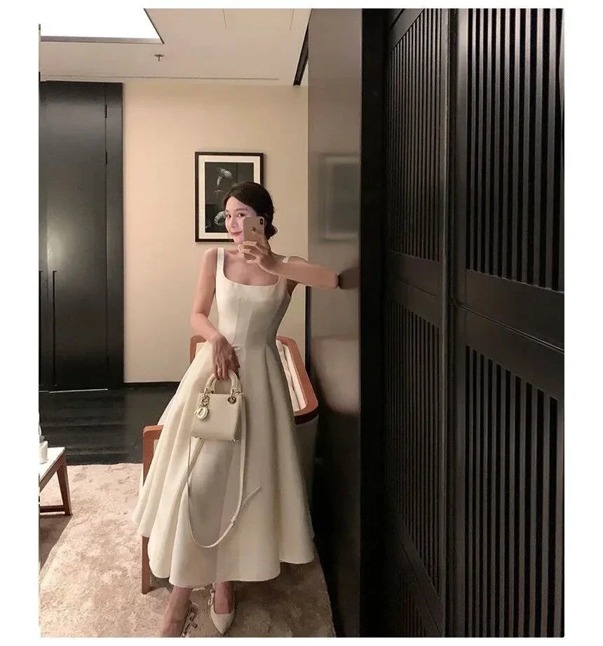 Woman taking a mirror selfie in an elegant white dress with matching handbag, ZAPDRESS fashion.