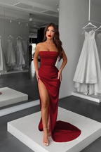 Woman in elegant red strapless evening gown with high slit at ZAPDRESS boutique, surrounded by white dresses.