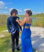 Couple in formal blue attire by a lake, outdoor sunlight, ZAPDRESS fashion inspiration