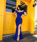 Woman in an elegant royal blue evening dress with a thigh-high slit by a yellow door, ZAPDRESS