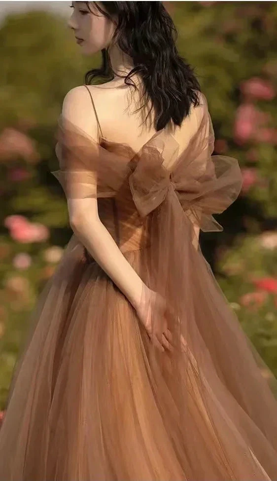 Woman in a brown tulle ZAPDRESS gown with a large bow, standing in a floral garden