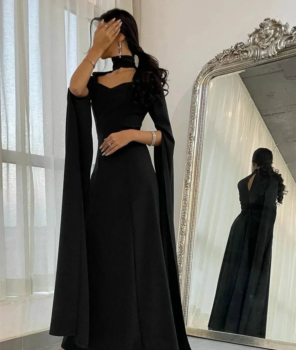 Woman in elegant black evening gown with dramatic sleeves posing by ornate mirror, ZAPDRESS