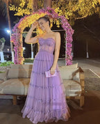 Woman in a lilac evening dress holding a clutch, standing by floral arch at night, ZAPDRESS