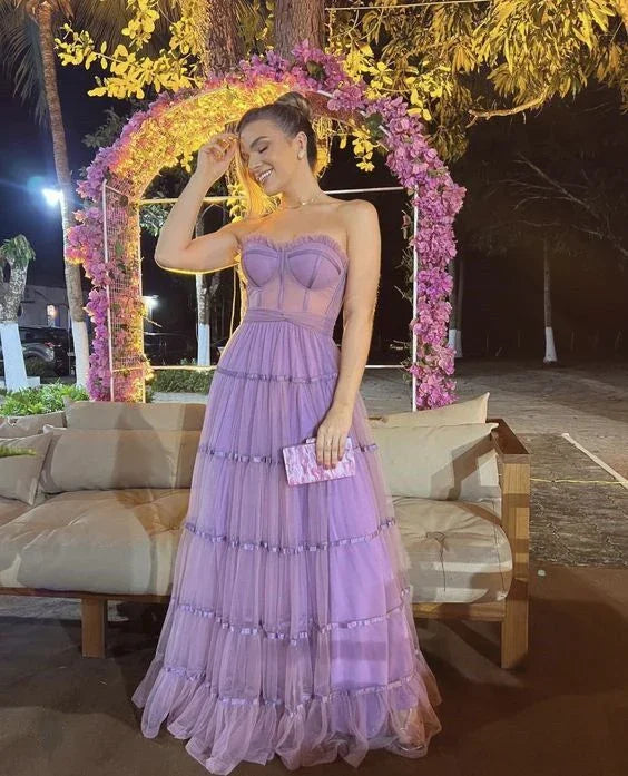Woman in a lilac tulle evening dress holding clutch, standing by floral arch, ZAPDRESS fashion