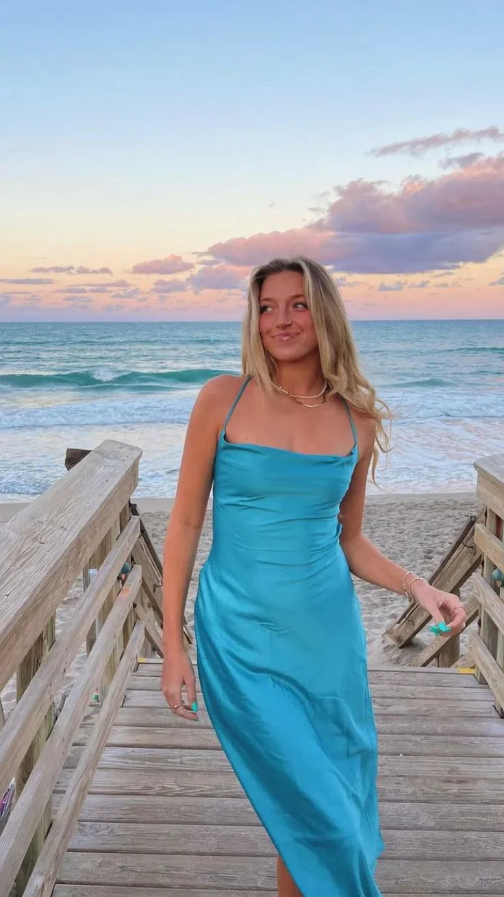 Woman in a blue satin dress on a wooden boardwalk by the ocean at sunset, ZAPDRESS fashion