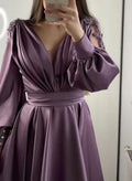 Woman wearing elegant mauve satin dress with beaded shoulders and pleated skirt from ZAPDRESS