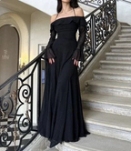 Woman wearing a long off-shoulder black dress on a staircase, ZAPDRESS fashion style