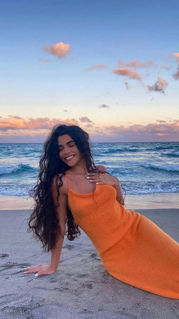 Woman in an orange dress smiling on the beach at sunset, ZAPDRESS fashion photo