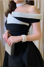 Elegant woman in black off-shoulder dress with pearl choker, bracelet, and clutch from ZAPDRESS
