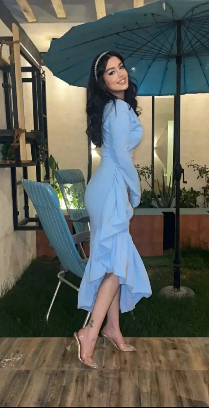 Woman in light blue ruffle dress and clear heels standing outdoors under blue umbrella, ZAPDRESS