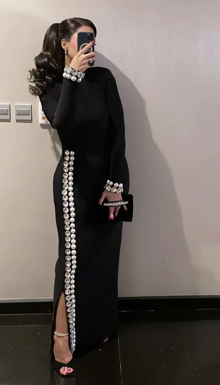 Woman in black ZAPDRESS gown with silver pearl accents, holding a clutch, taking mirror selfie