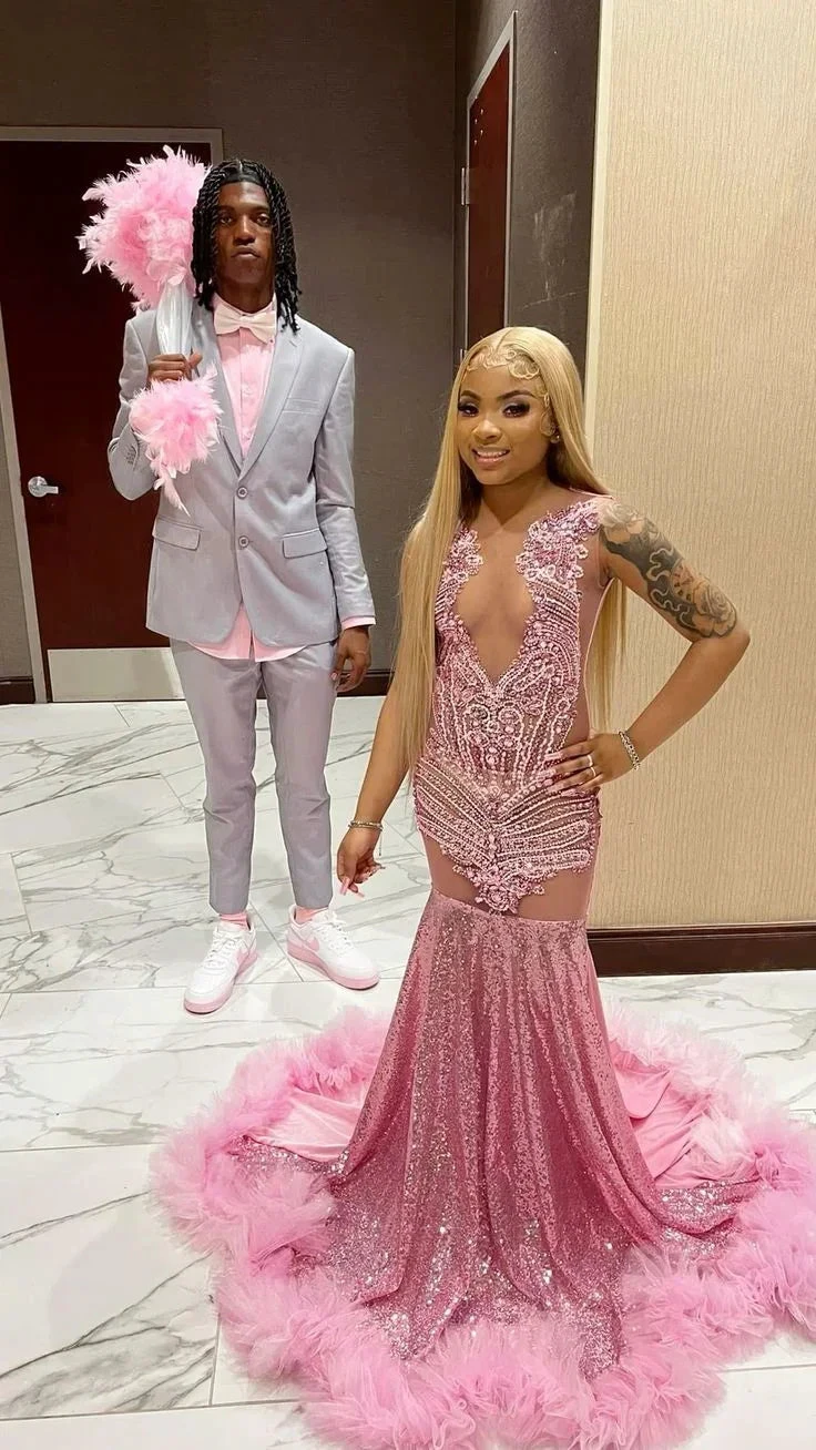 Couple in formal wear, woman in sparkling pink mermaid dress with feathers, man in light gray suit, perfect for ZAPDRESS prom fashion.