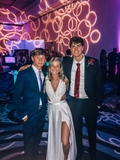 Three young adults in formal prom attire at an event with decorative lighting, ZAPDRESS style