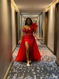 Woman in vibrant red evening dress with thigh-high slit and floral detail, walking indoors