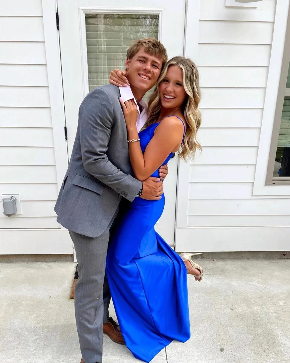 Smiling couple posing outdoors, woman in vibrant blue formal dress, man in gray suit, ZAPDRESS style
