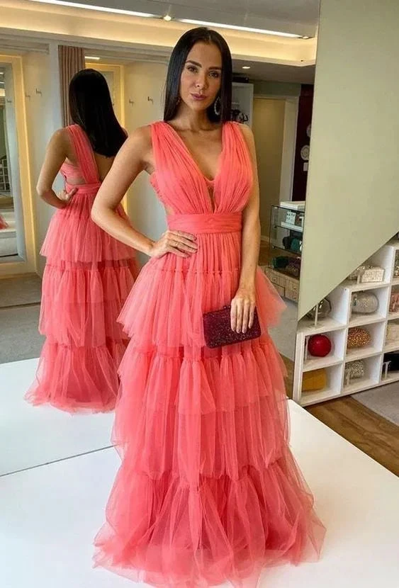 Woman in a tiered pink tulle evening gown holding a clutch, standing in a boutique
