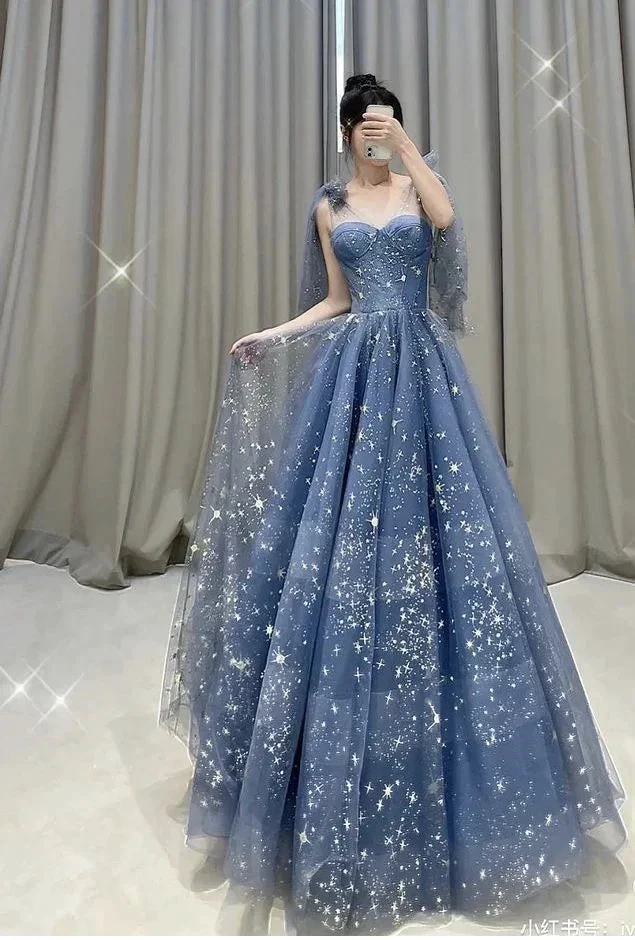 Woman in a sparkly blue ball gown with star patterns, standing indoors, ZAPDRESS fashion