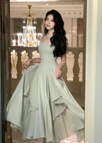 Elegant woman in flowing light green dress poses in luxurious setting, ZAPDRESS fashion