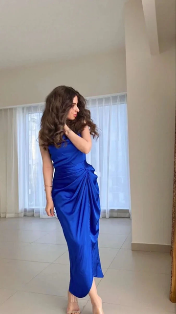 Woman in vibrant blue satin draped dress standing indoors, ZAPDRESS fashion