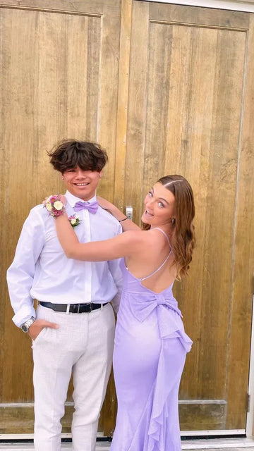 Smiling couple in lilac prom outfits posing in front of wooden doors, ZAPDRESS style