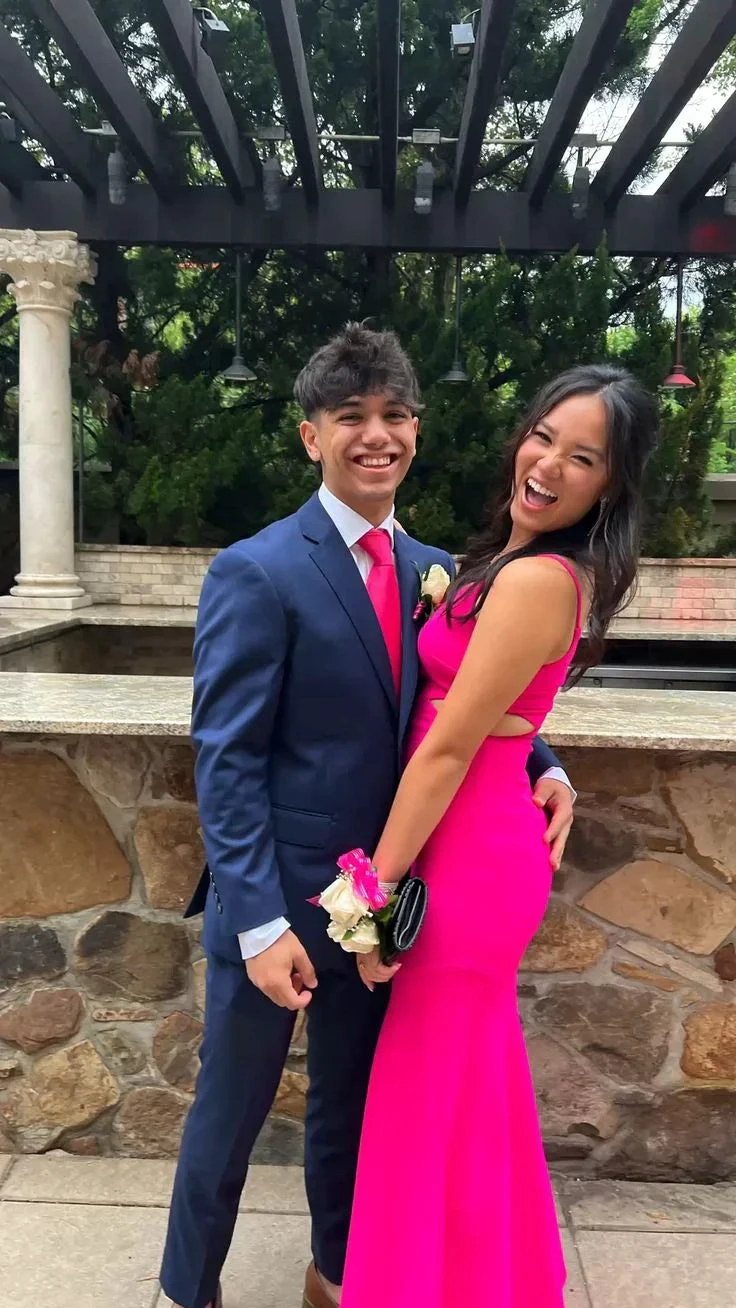 Smiling couple at outdoor event, woman in bright pink dress, ZAPDRESS formal style