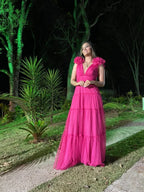 Woman in vibrant pink evening dress standing outdoors by green trees at night, ZAPDRESS fashion