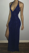 Woman wearing a sparkly navy blue halter dress with deep V neckline and thigh-high slit
