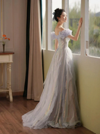 Woman in iridescent off-shoulder evening gown standing by window, ZAPDRESS fashion