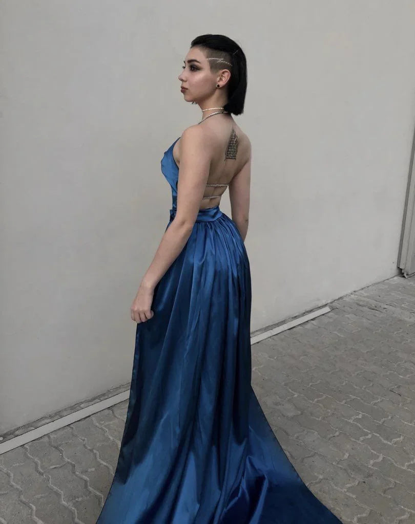Woman in a blue satin evening gown with open back, standing on stone pavement, ZAPDRESS fashion