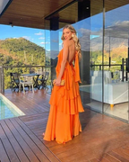 Woman in a bright orange ruffle dress on a wooden deck with mountain views, ZAPDRESS fashion
