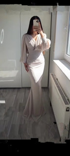 Woman wearing a long-sleeve beige evening gown in a modern room, ZAPDRESS fashion