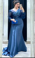 Woman in elegant blue evening gown with lace sleeves posing with blue clutch in mirror selfie