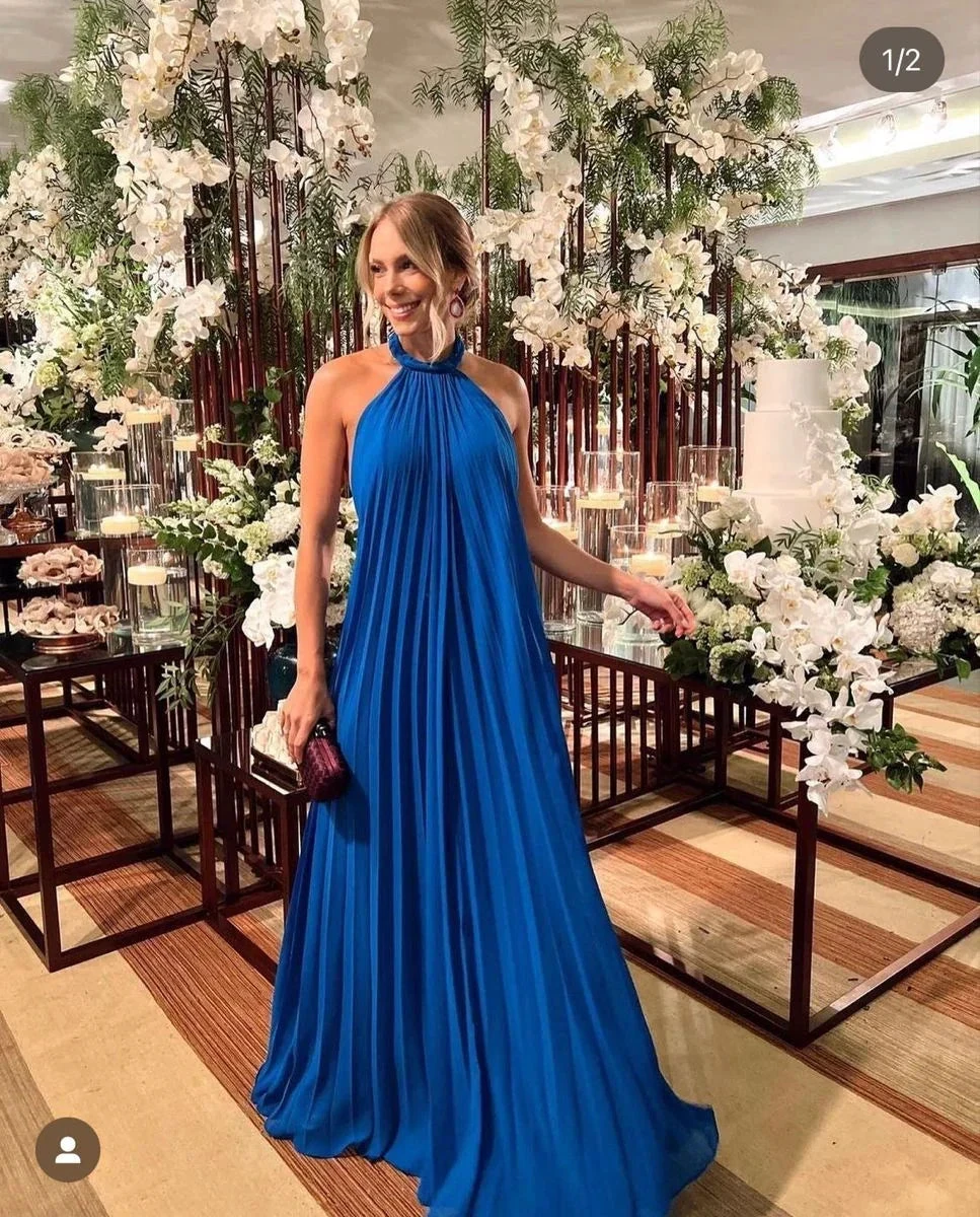 Woman in elegant blue halter maxi dress at floral event, ZAPDRESS fashion