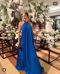 Woman in elegant blue halter maxi dress at floral event, ZAPDRESS fashion
