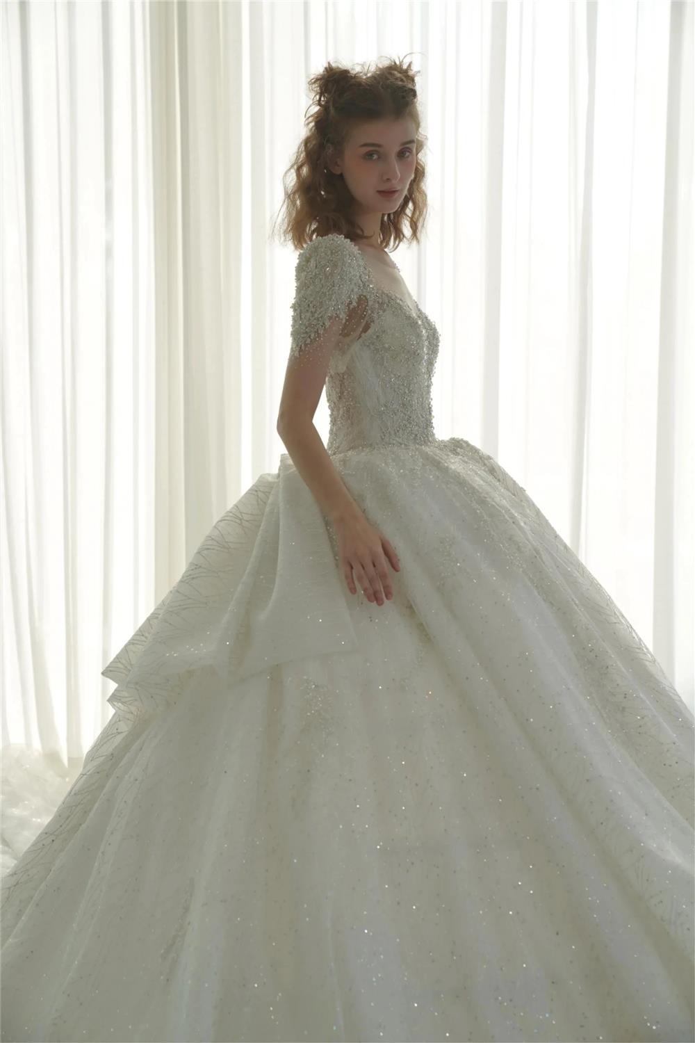 Vestido de Noiva Luminoso com Saia Rodada, Decote Ilusão, Tule, Bordado com Miçangas de Cristal e Cauda com Laço nas Costas Q-6023