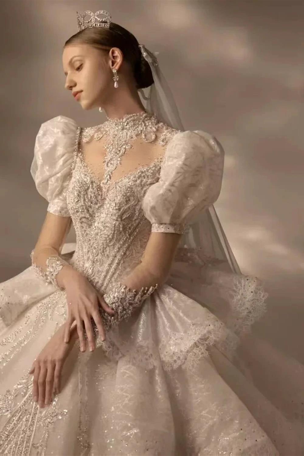 Vestido de novia de tul con cuello alto, mangas abullonadas, bordado de lentejuelas y cola con volantes en capas Q6020
