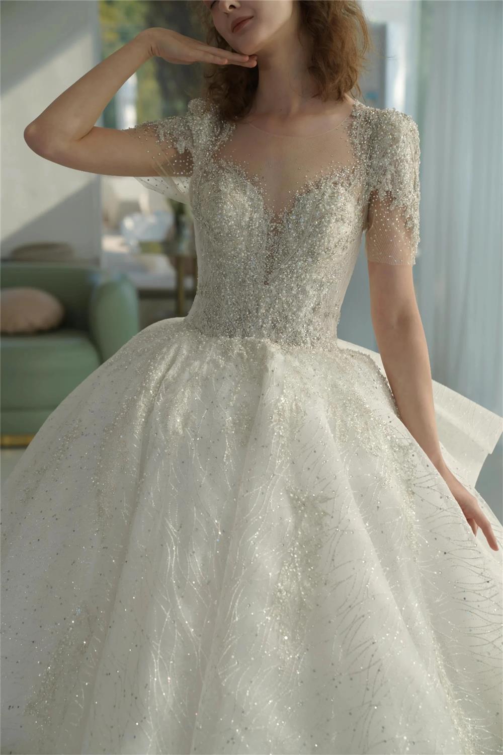 Vestido de Noiva Luminoso com Saia Rodada, Decote Ilusão, Tule, Bordado com Miçangas de Cristal e Cauda com Laço nas Costas Q-6023