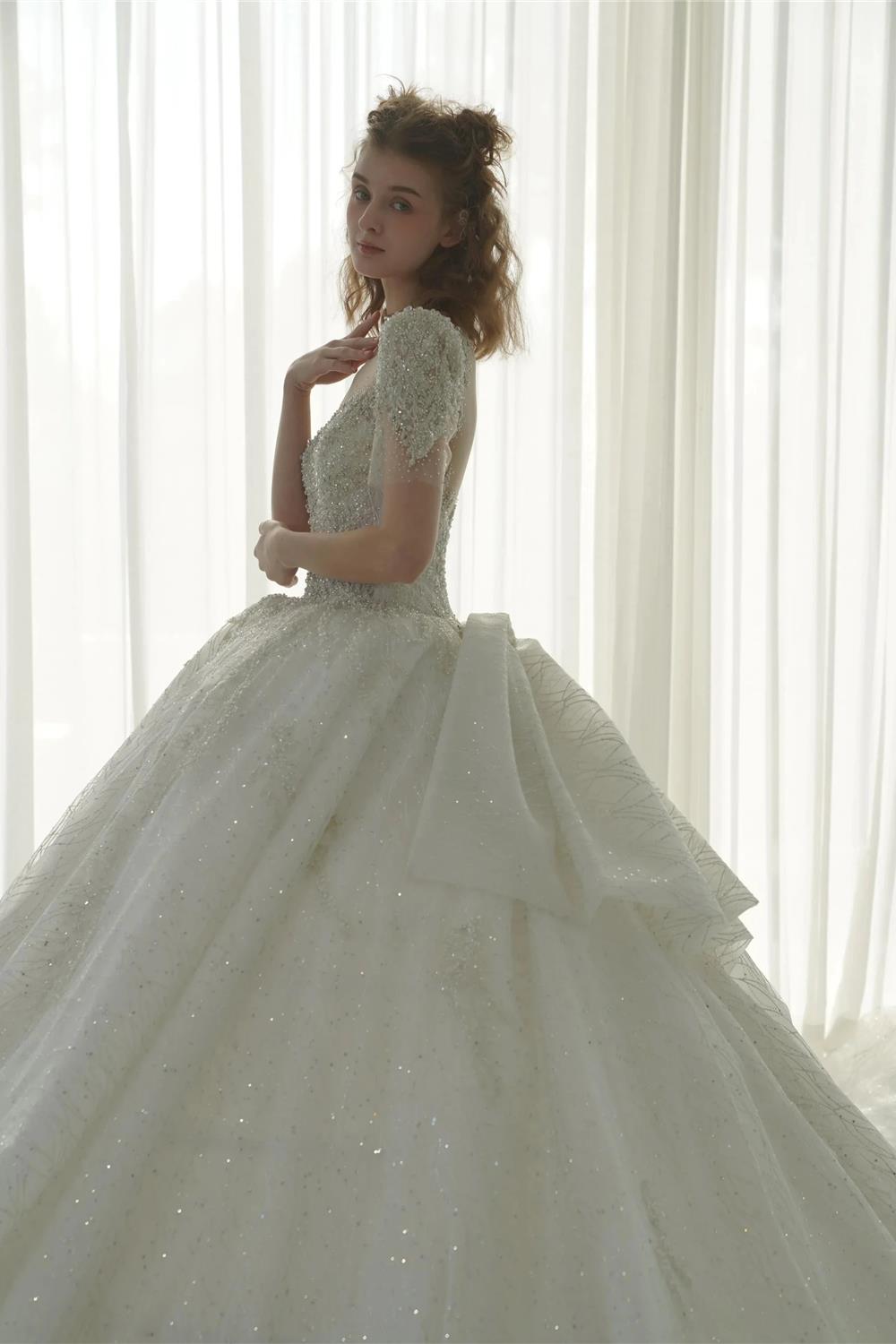 Vestido de Noiva Luminoso com Saia Rodada, Decote Ilusão, Tule, Bordado com Miçangas de Cristal e Cauda com Laço nas Costas Q-6023