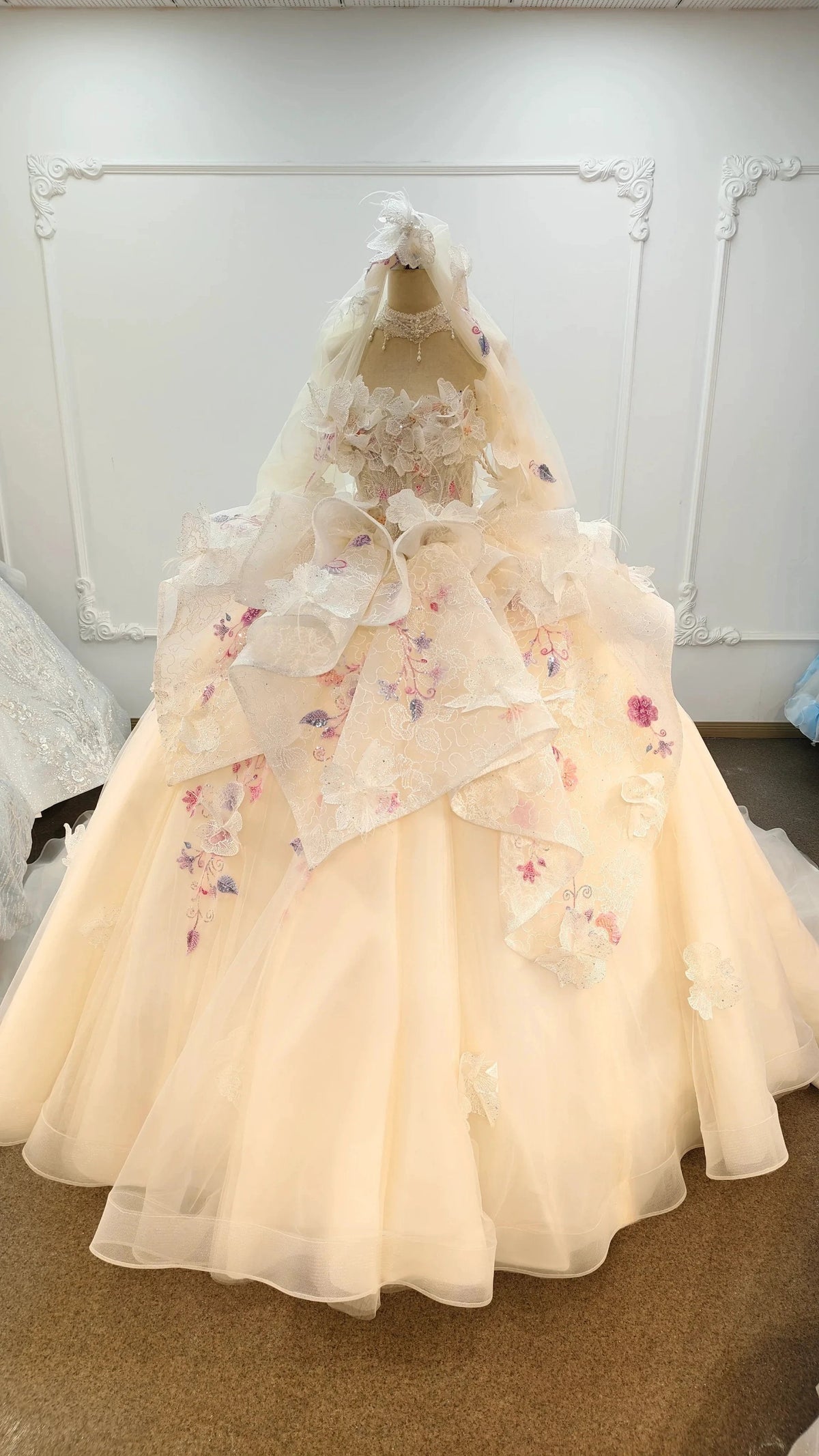 Abito da ballo senza spalline color rosa pesca con gonna ricamata e mantella di tulle floreale