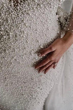 Abito da sposa con maniche lunghe avorio, scollo a V, bottoni, strascico spedibile e perle completamente ricoperte